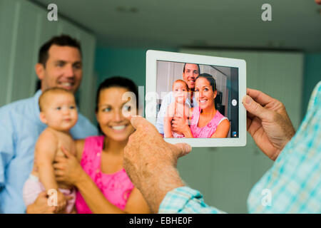 Over shoulder portrait of mid adult couple and baby daughter taken on digital tablet Stock Photo