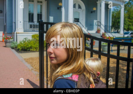 Schoolgirl and younger brother at school gate Stock Photo