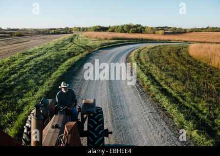 High angle view of senior male farmer driving tractor on rural road, Plattsburg, Missouri, USA Stock Photo