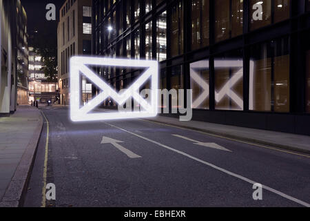 Glowing email icon in street at night, London UK Stock Photo