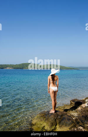 Rear view of young woman wearing bikini gazing out to sea, Milna, Brac, Croatia Stock Photo
