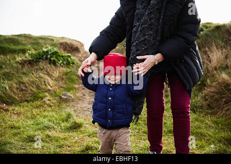 Male toddler and mother holding hands walking in dune