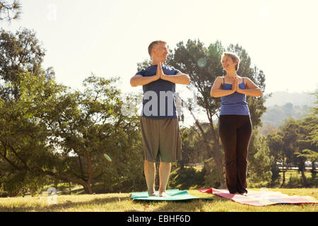 Mature couple practicing yoga in park Stock Photo