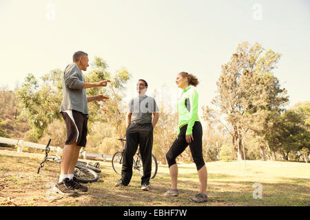 Three mature cyclists chatting in park Stock Photo