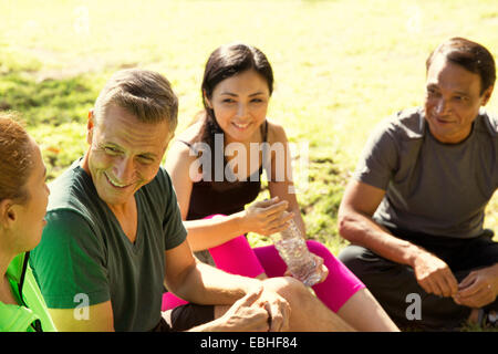 Four mature male and female runners taking a break in park Stock Photo