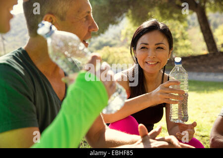 Mature male and female runners taking a water break in park Stock Photo