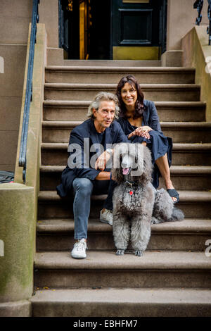 Portrait of mature couple and their poodle sitting on apartment stairway Stock Photo