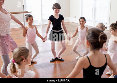 Children and teacher in a circle practicing ballet in ballet school Stock Photo