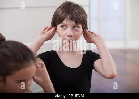 Girl with holding ears pulling a face in ballet school Stock Photo