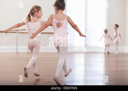 Rear view of girls practicing jump in ballet school Stock Photo