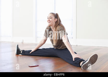 Teenage girl warming up and doing the splits in ballet school