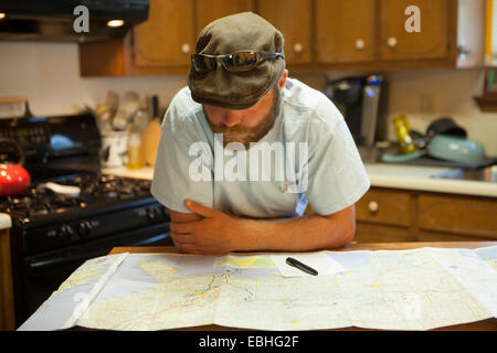 Man studying map of USA at kitchen table Stock Photo