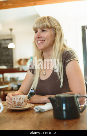 Mid adult woman drinking tea in country store cafe Stock Photo