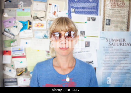 Portrait of mid adult woman in front of community notice board Stock Photo