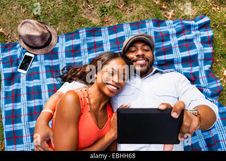 Couple lying on grass watching movie on tablet Stock Photo