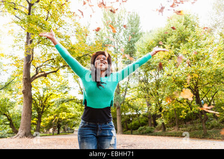 Woman throwing autumn leaves into air