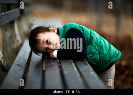 Portrait of male toddler leaning forward on park bench Stock Photo