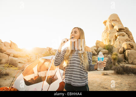 Woman getting ready to bed down in tent, Joshua Tree National Park, California, US Stock Photo