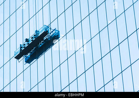 Suspended window cleaning platform on glass building Stock Photo