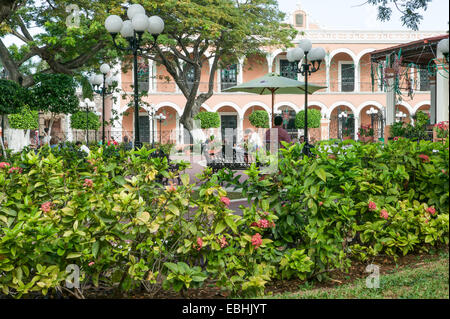 Campeche park, with shade trees, green umbrella, globe lamps, Christmas decorations, bordered by flowers, Spanish Colonial building, Campeche, Mexico. Stock Photo