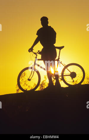 Silhouette of Male Biker at sunset Stock Photo