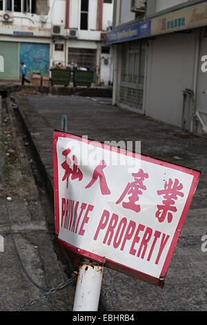 Private property in English and Chinese on broken post in road, Miri, Malaysia Stock Photo