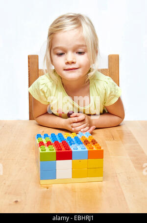 Portrait of Little child blond girl playing with plastic building blocks, white background Stock Photo