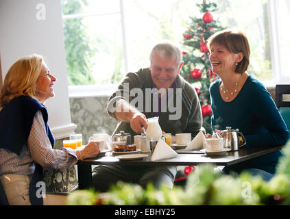 Festive friends having tea and coffee at Christmas one man and two women Stock Photo