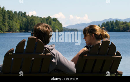 Young couple man woman sitting in double Adirondack chair over looking Long Lake New York USA. Adirondack State Park Adirondacks Stock Photo