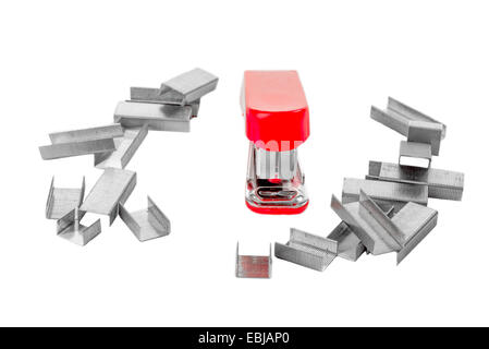 Little red stapler on white isolated background, facing the viewer, and surrounded by staples. Stock Photo