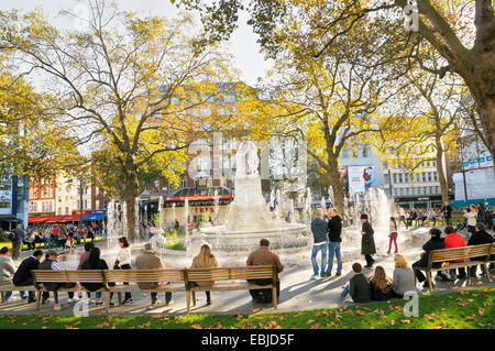 Leicester Square, London.  People relaxing around the William Shakespeare statue and fountain in Leicester Square Gardens. Stock Photo