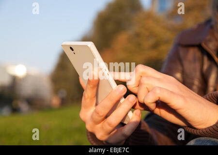 woman's hand holding smartphone in evening Stock Photo