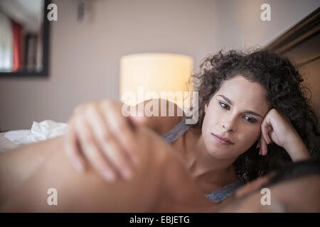Young woman in bed with hand on man's shoulder