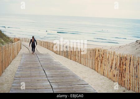 Surfer with surfboard walking to beach, Lacanau, France Stock Photo