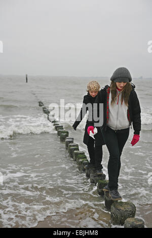 Balancing two women on one leg in backyard, wearing pink tops, purple ...