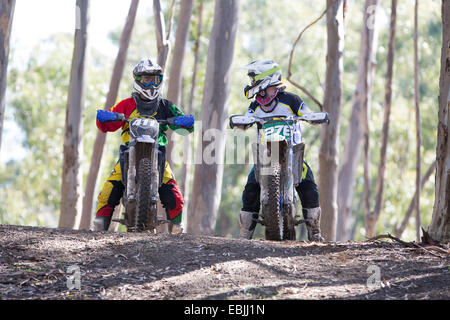 Two young male motocross riders chatting in forest Stock Photo