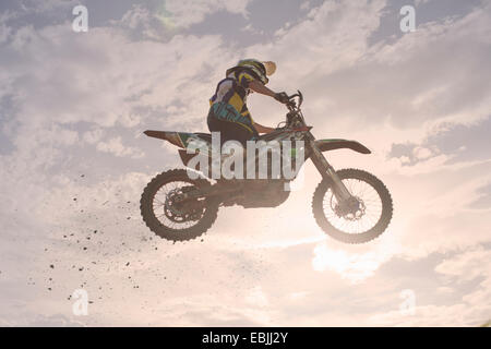 Silhouetted young male motocross racer jumping mid air Stock Photo