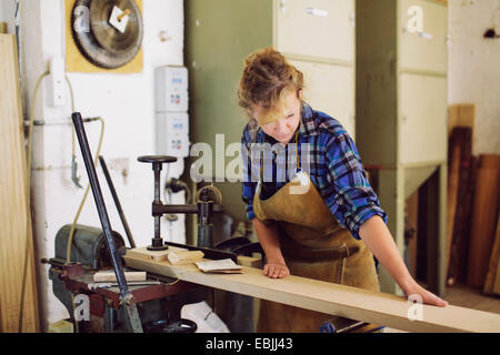 Young craftswoman checking wood in pipe organ workshop Stock Photo