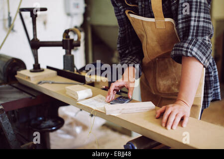 Cropped shot of young craftswoman using calculator in pipe organ workshop Stock Photo