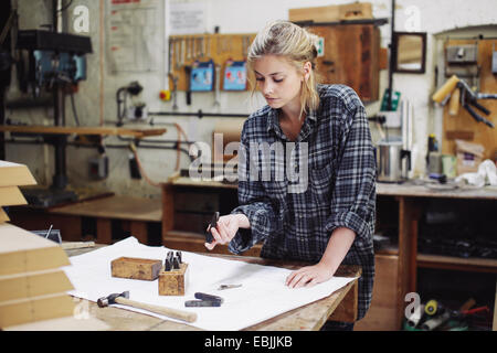 Young craftswoman checking components on workbench in pipe organ workshop Stock Photo