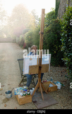 Mature male artist painting canvas on house driveway Stock Photo