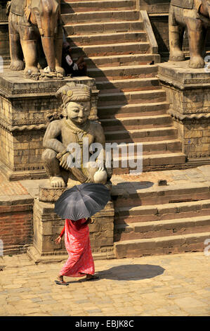 woman with an umbrella serving as a sunshade crossing the Bhaktapur Durbar Square at the royal palace, Nepal, Bhaktapur Stock Photo