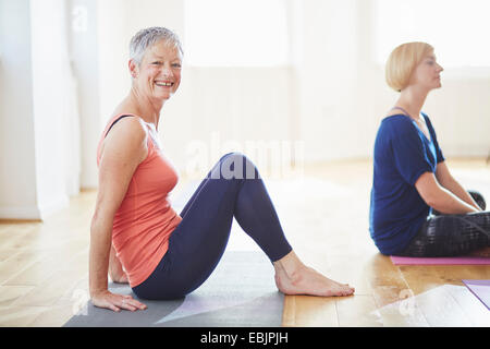 Portrait of mature woman sitting on floor in pilates class Stock Photo