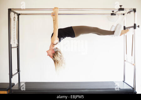 Mature woman practicing pilates on trapeze table in pilates gym Stock Photo