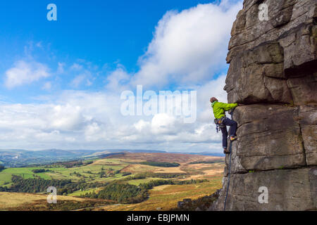 Rock climber on sheer cliff face, with panorama view at Stanage Edge, Peak District, Derbyshire Stock Photo