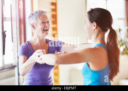 Young female student laughing with teacher in pilates gym Stock Photo