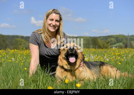 mixed breed dog (Canis lupus f. familiaris), young blond woman and her dog lying in a meadow, Germany Stock Photo