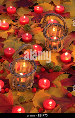 burning tea candles and two lanterns in autumn foliage Stock Photo