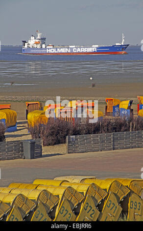 roofed wicker beach chairs on sandy beach, cargo ship in background, Germany, Lower Saxony, Cuxhaven Stock Photo