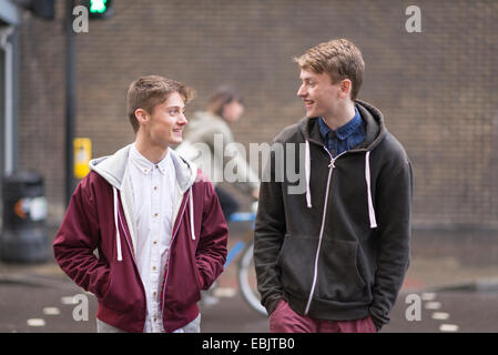 Two male friends crossing road Stock Photo